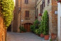 Pienza, Italy Ã¢â¬â May 27, 2017: Beautiful narrow street with sunlight and flowers in the village of Pienza, Italy Royalty Free Stock Photo